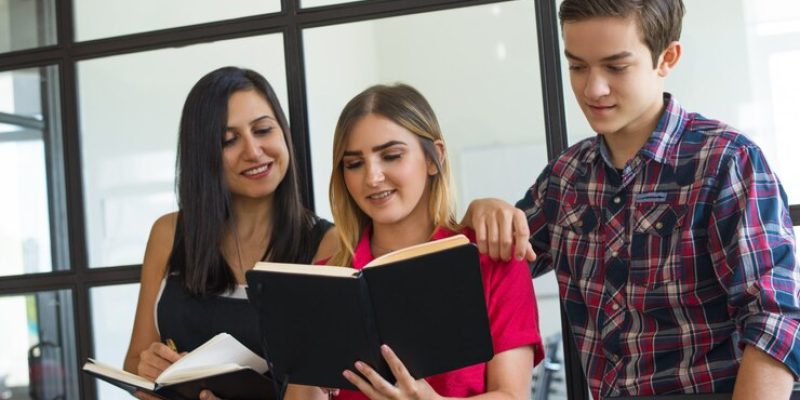 portrait-happy-young-students-sharing-homework-college_1262-17982